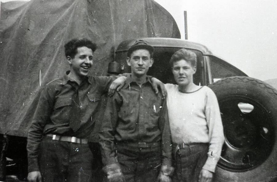 Three CCC men pose in front of a cab of a covered pickup truck.