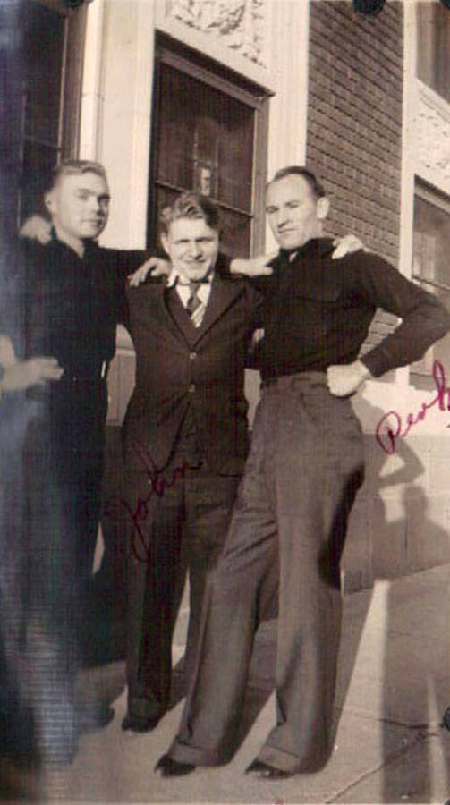 Three CCC men standing in front of a official-looking building. Writing on the photo reads: ' John' and 'Duck'. Writing under the photo reads: 'Moscow, ID'.
