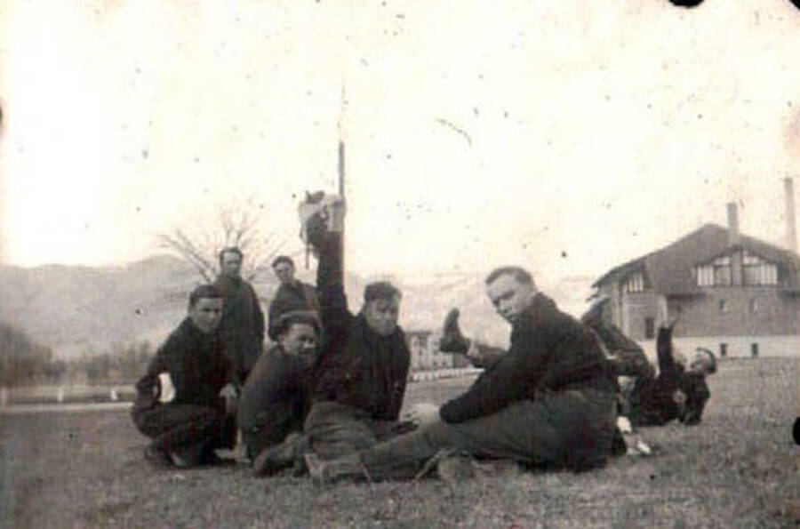 Several CCC men lounging on the lawn in front of a CCC building. Writing under the photo reads: 'Lewiston, Idaho'.