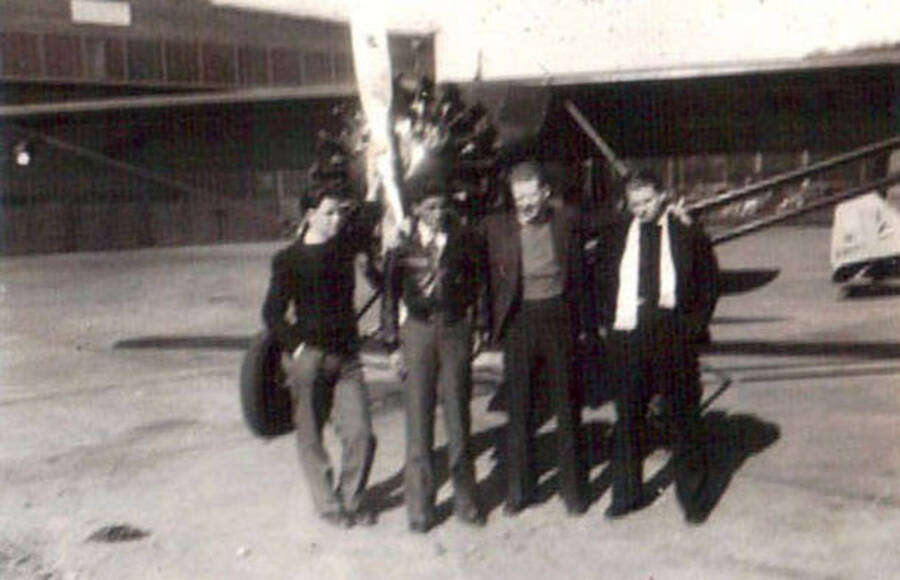 Four men standing in front of an airplane. Some of the men could be CCC enrollees, others could be pilots, or they could be both. Writing under the photo reads: 'Seattle, Washington'.