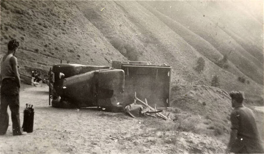 Overturned truck in the process of being righted. Writing underneath each photo is one word that makes the sentence: 'This truck overturned by accident' Word on this image is: 'By'.