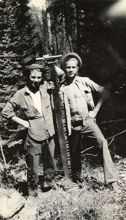 Two CCC men with a crosscut saw. Writing below the photo reads: 'Me - 'Tex''.