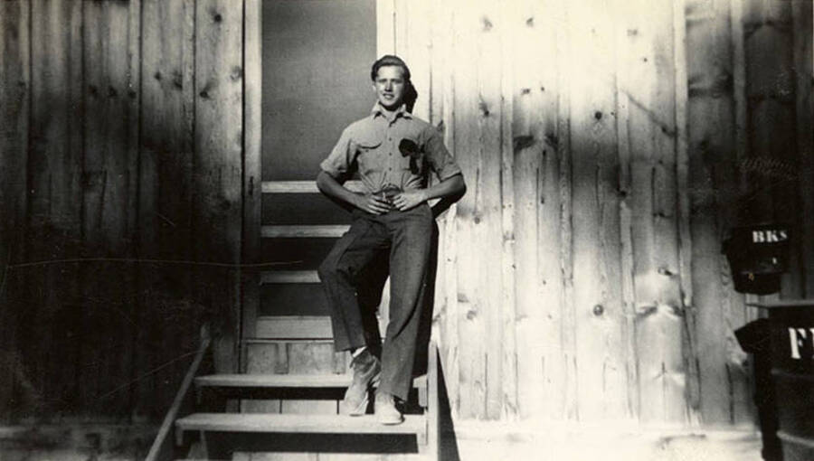 Portrait of a CCC man in front of the door to the barracks. Writing under the photo reads: 'Tex'.