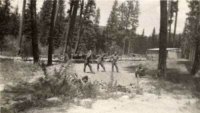 Three members of a CCC work crew posing for the camera, two with hand tools, while their supervisor sits nearby. Writing under the photo reads: '3 of us and - Cecil'.