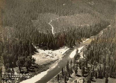 Aerial view of Rock City CCC Camp and surrounding scenery, including areas recently logged and/or burned. Writing on the photo reads: '17-241 Rock City CCC Camp F-153 Company 1504 Air photo by Leo's Studio'.