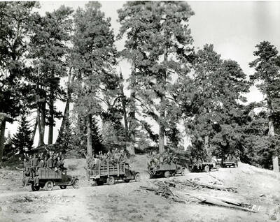 CCC work crew loaded onto five open trucks. Hand written caption on back: CCC enrollees on trucks at Shafter Butte north of [?] neg #90-017