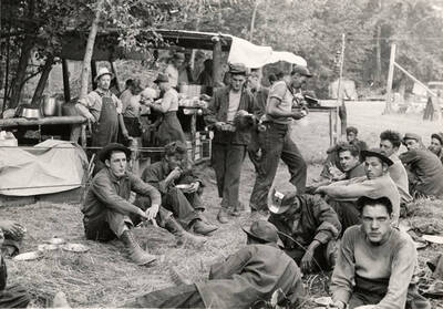 Group photo of a CCC fire crew resting and eating after fighting the Spirit Lake Fire. Stamp on back of photo reads: 'If this photo is reproduced credit must be given as follows: 'Photo by K.D. Swan, courtesy U.S. Department of Agriculture, Forest Service.''