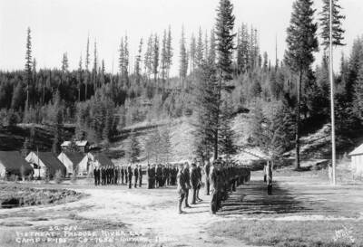 CCC Company 1655 standing at attention in front of an officer and the flagpole. The writing on the photo reads '22-058 Retreat - Palouse River CCC Camp F-185 Co-1655 - Harvard, Idaho. Leo's Studio' Writing on the back of the photo reads: '25-13-51 19305 [unidentifiable name] of N. Idaho Harvard Palouse R.' The stamp reads: ' Leo's Studio University Place Spokane, Washington'.