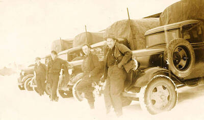 Four CCC trucks parked in a row with their drivers posed in front. Snow covers the ground and truck tires.