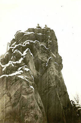A shot of two CCC men atop a large snow-covered rock formation.