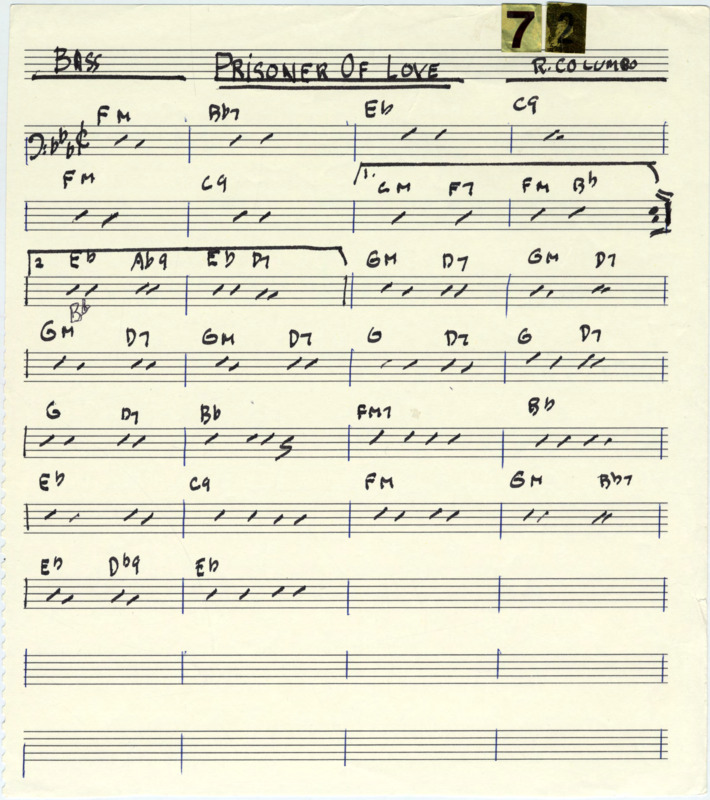 Loose page with printed music staves. At the top, "Bass" and "R. Columbo," are written and underlined in black marker. "Prisoner Of Love" is written and underlined twice in black marker. In the top right corner are "7" and "2" gold reflective stickers. Written in black marker is a bass clef, dashes to indicate notes, the key signature (Bb, Eb, Ab), time signature (cut time), and a repeat sign with 1st and 2nd endings. Measure lines are written in blue pen. "Prisoner of love" (1931) was composed by Russ Columbo (1908-1934), Clarence Gaskill (1892-1948), and Leo Robin (1900-1984).
