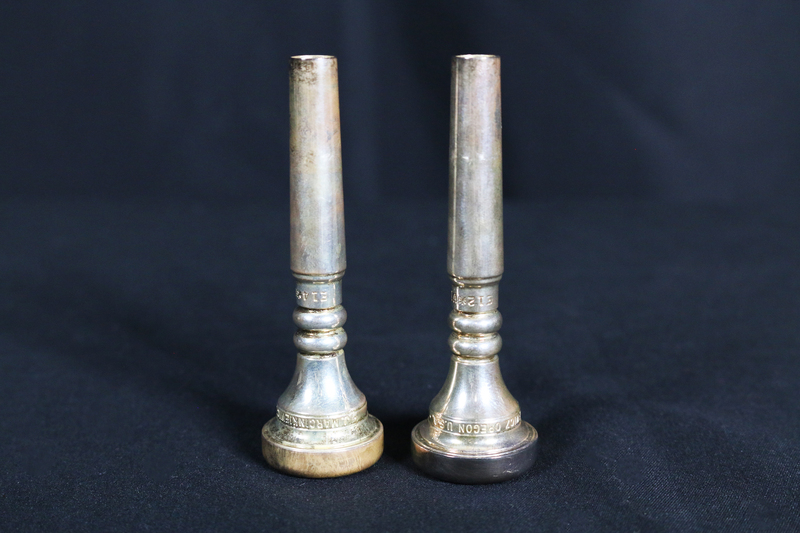 Two metal trumpet mouthpieces.