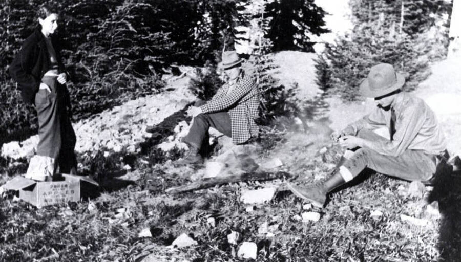 L. Delroy Flores and Jim Kauffman seated on ground. June Kauffman standing. Near Dixie, Idaho.