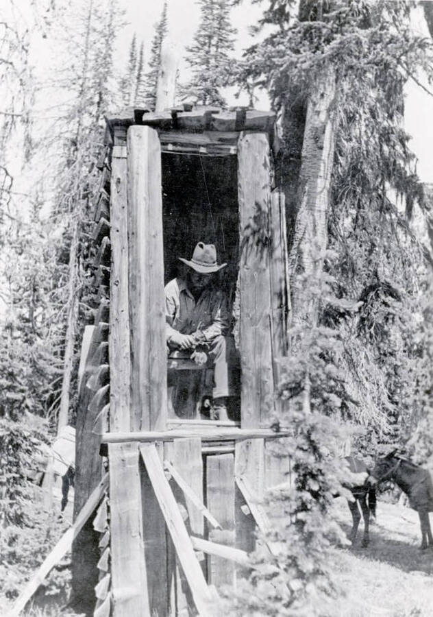 Pick Ward demonstrating use of a backcountry outhouse, built for easy access in deep snow. Near Dixie, Idaho.