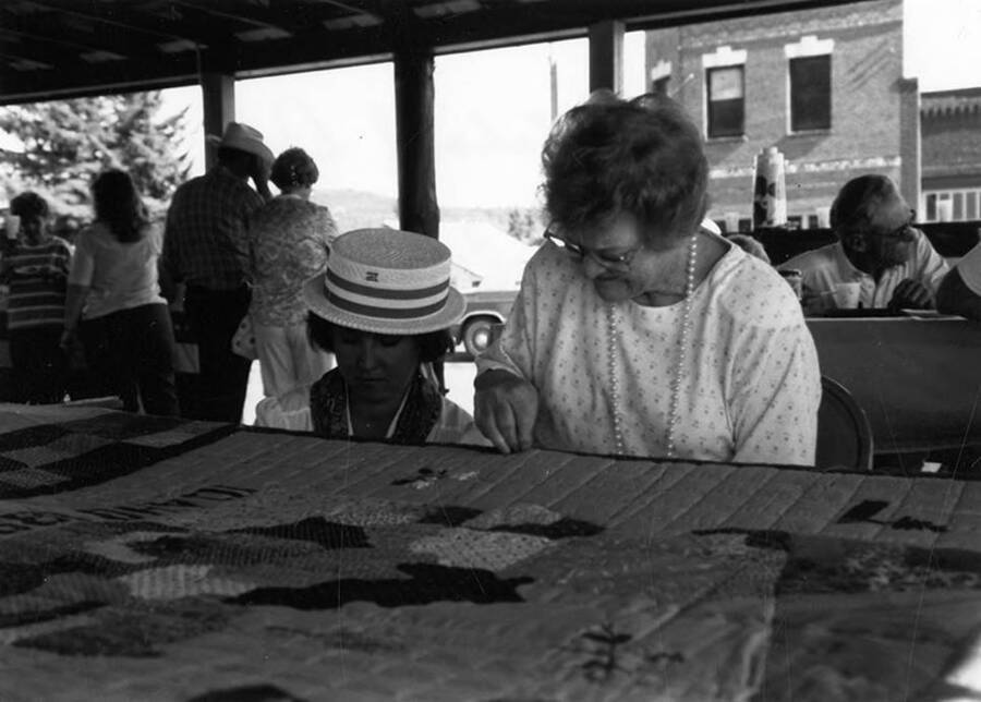 Two women work on a quilt during Bovill's Statehood Day celebration.