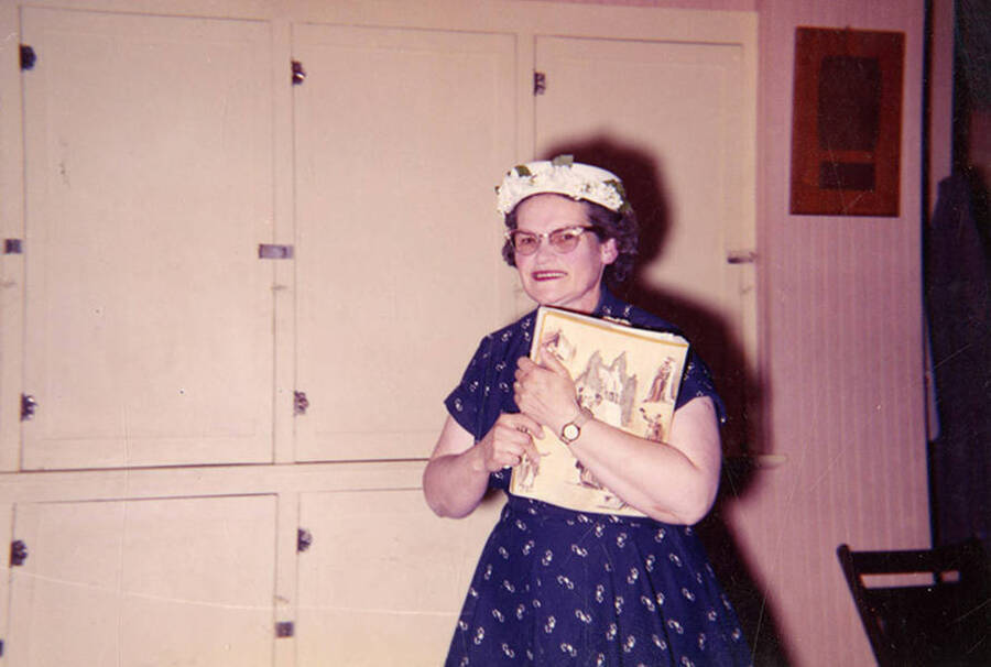 Bovill teacher, Phyllis Cox Nelson, poses for a picture in front of cupboards with a notebook in hand.
