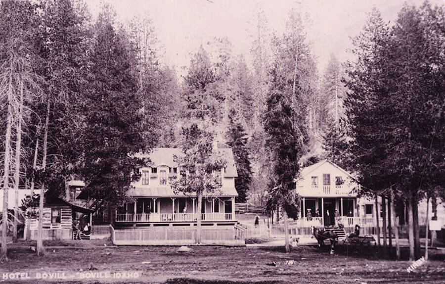 The Bovill Hotel surrounded by trees and with people out front.
