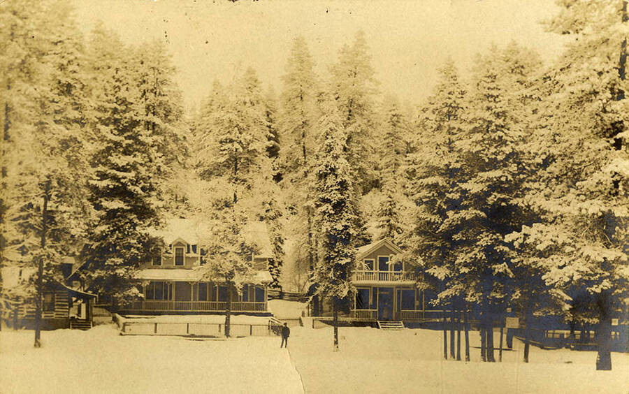 A group of Bovill houses surrounded by trees and covered in snow.