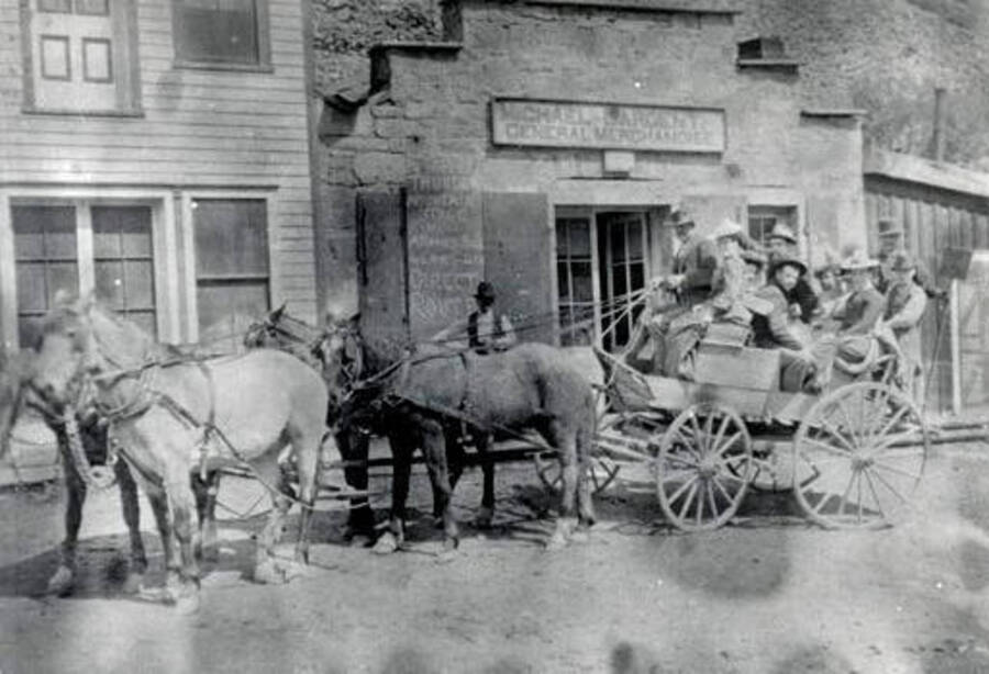Buggy full of men and women pulled by four horses. Challis, Idaho.