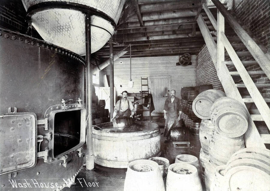 Two men washing barrels in a large tub