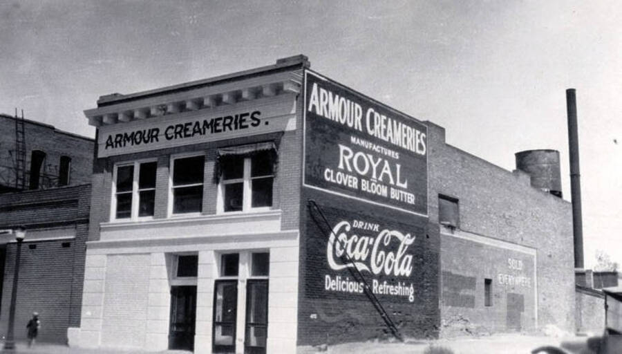 Sign also says 'Armour Creameries Manufactures Royal Clover Bloom Butter' and 'Drink Coca-Cola, Delicious - Refreshing'