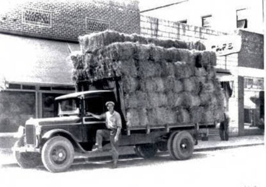 Loaded truck of hay parked on street in front of a caf. Orofino, Idaho.