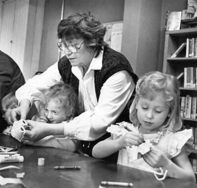 Diane Becker, the first supervisor at the Bovill Library and city clerk, helps children during story time.
