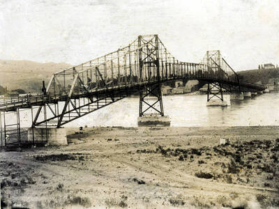 First Snake River bridge under construction'. Visible: Booth Flour Mill, Masonic Temple, C.P. Coburn shed and barn