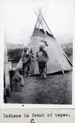 Rev. Stephens Reubens speaking, Indian in headdress in front of tepee