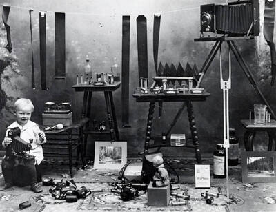 Harold, son of A.M. Whelchel, holding camera. Also shows film, tables, chemicals, etc.