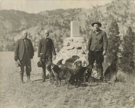Gov. Baldridge, Dave Lewis, Stanley A. Easton (and dogs) pose next to a headstone at the Sheepeater Battlefield on Soldier Bar.