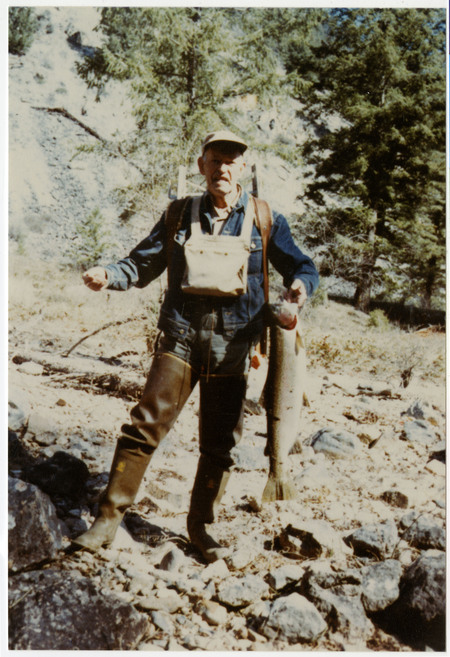 Jess Taylor with waders and fishing gear holding a large trout.
