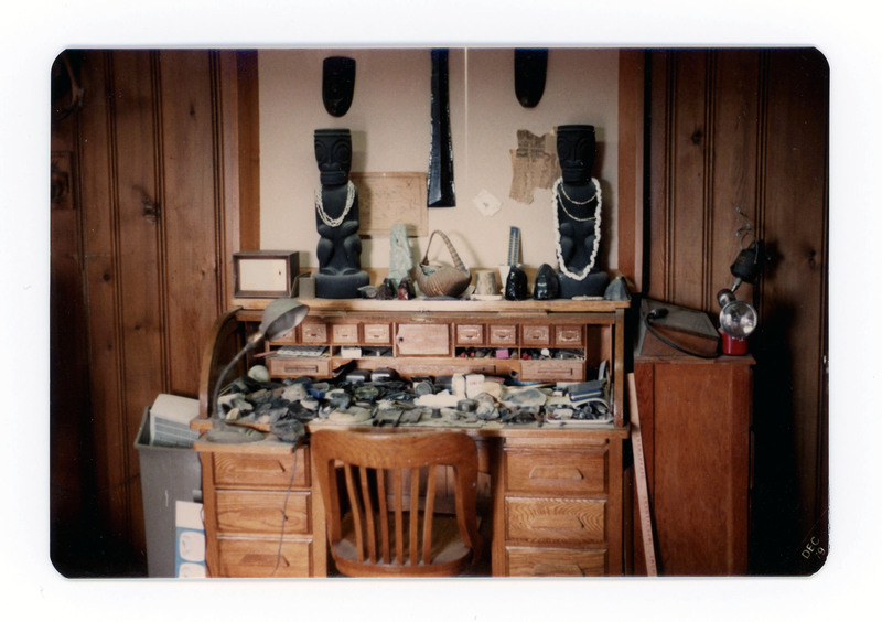 The front of a postcard decorated with a picture of a desk covered with lithic artifacts.