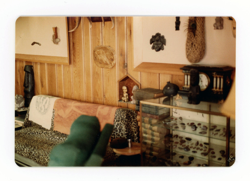 The front of a postcard decorated with a picture of a living room and lithic display.