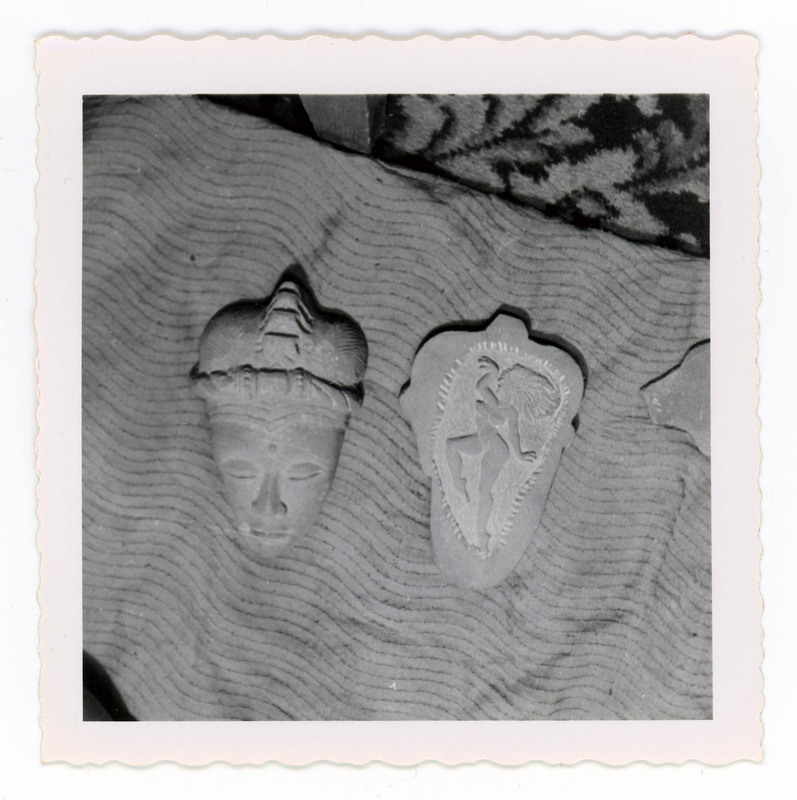 A printed picture of a Mayan stone mask next to a stone engraving of a woman.