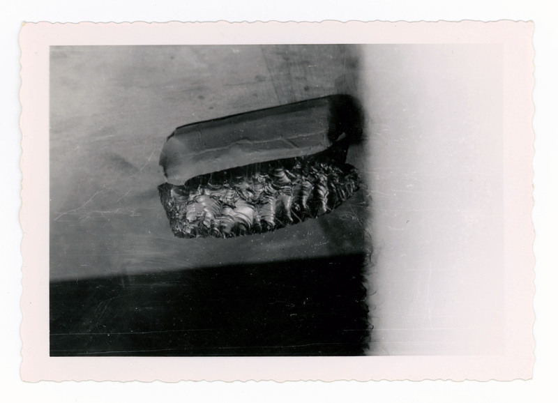 A printed picture of a lithic biface resting on a piece of clay.