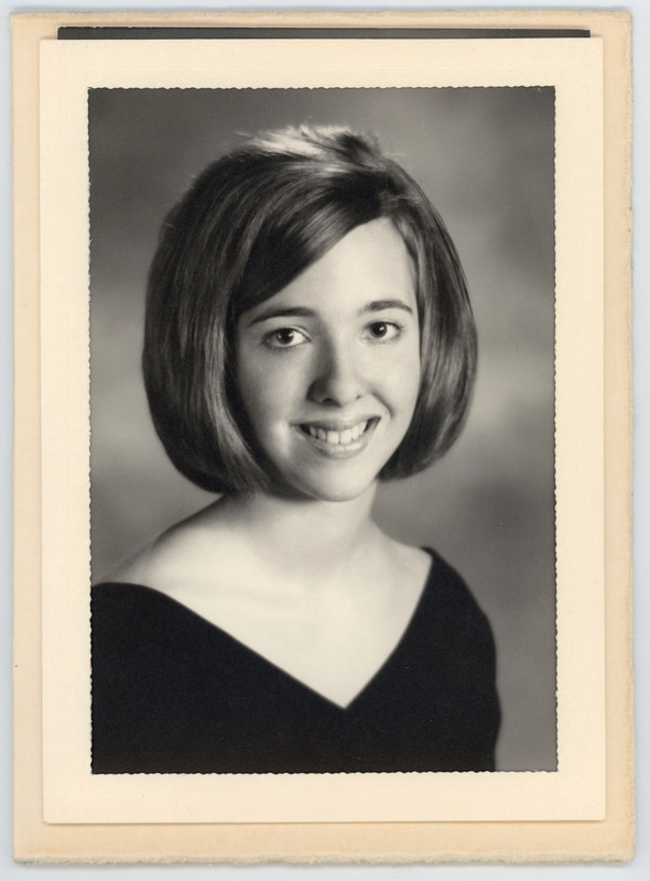 A headshot of a young woman with a short haircut in front of a grey wall.