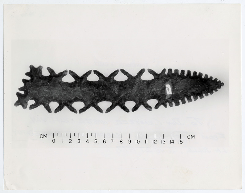 A lithic point with intricate serration next to a scale labelled "648". The back of the photo lists the image as property of the University of California, San Diego. It is signed "To Donald "Don" E. Crabtree, Master Craftsman, From Ted Folsom".