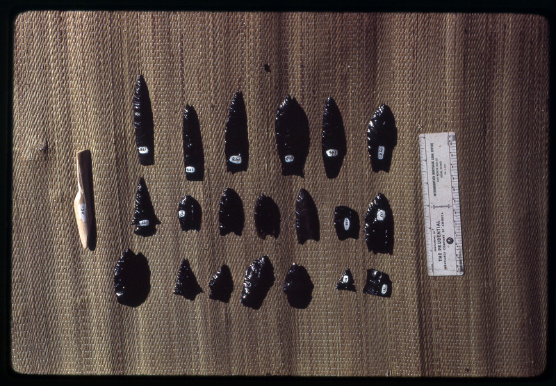 A photographic slide of a series of obsidian points and debitage accompanied by a measuring scale.