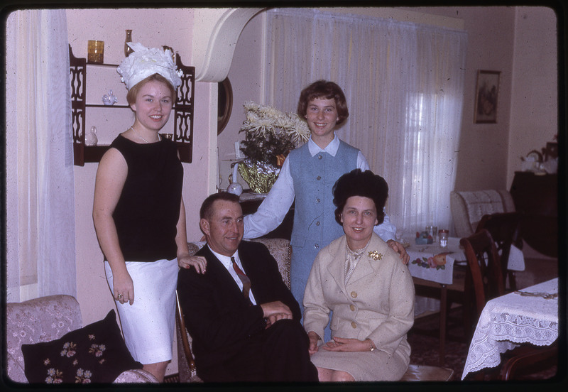 A photographic slide of four people smiling, dressed up for a party.