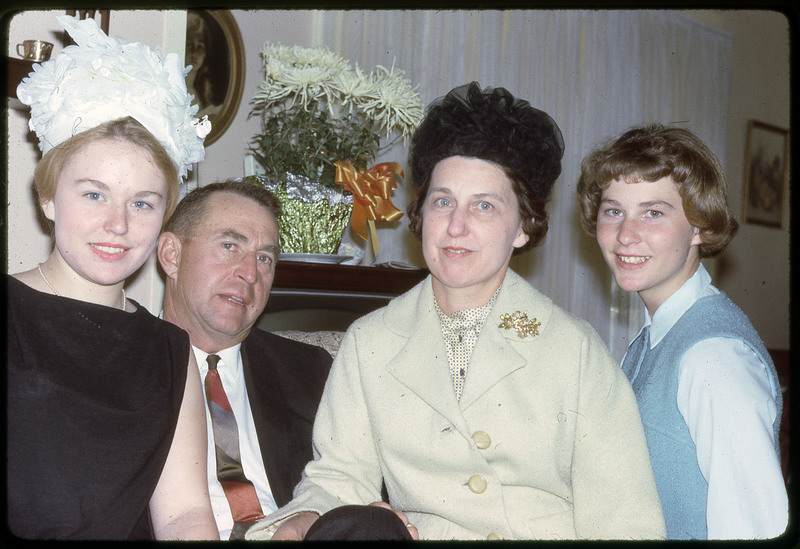 A photographic slide of four people smiling, dressed up for a party.