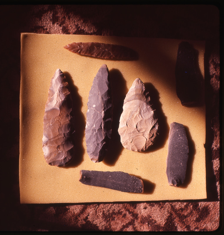 A photographic slide of a set of assorted lithic bifaces, cores, and blades.