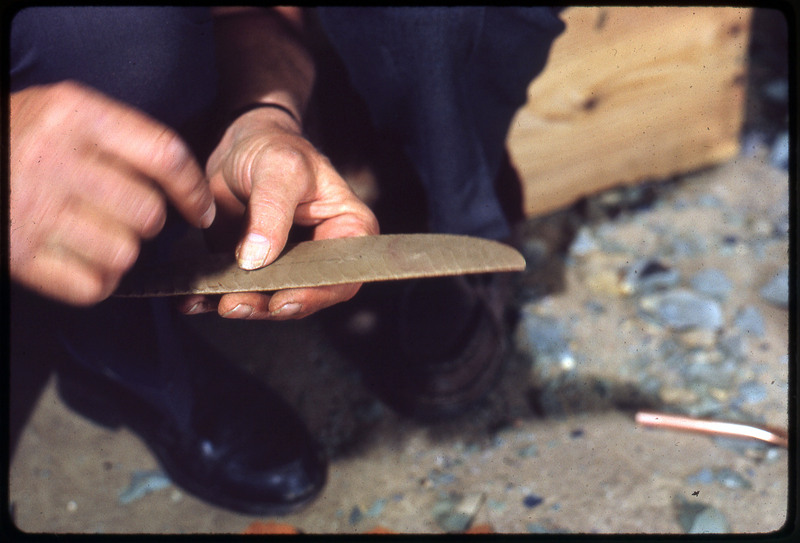 A photographic slide of a set of hands holding a lithic biface.