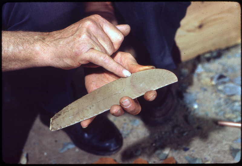 A photographic slide of a set of hands holding a lithic biface.