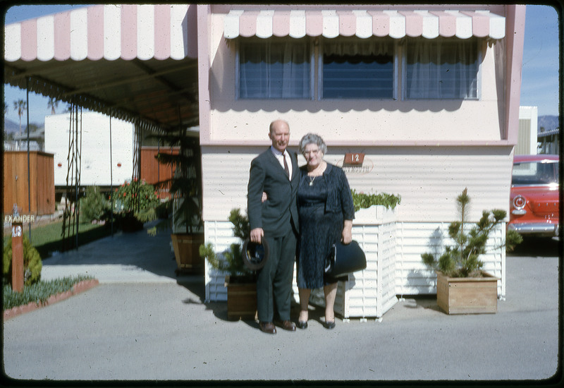 A photographic slide of a man and a woman standing in front of a decorated RV lot.