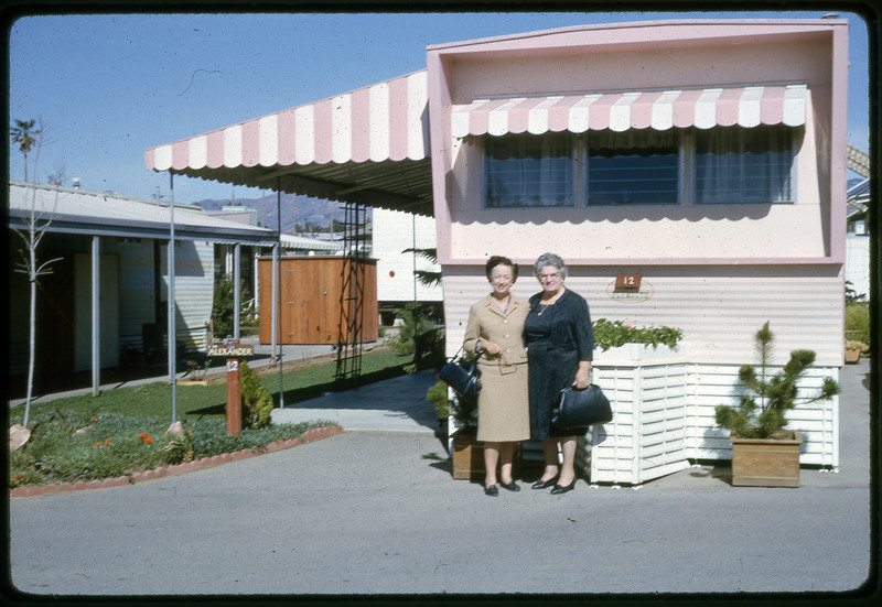 A photographic slide of two women standing in front of a decorated RV lot.