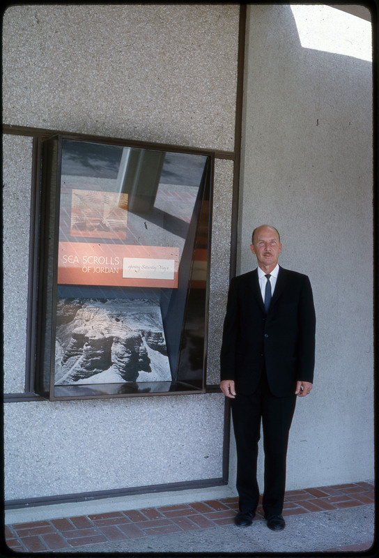 A photographic slide of Don E. Crabtree standing in front of an exhibit on the Sea Scrolls of Jordan.