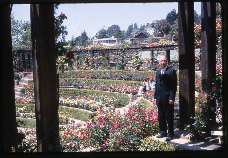 A photographic slide of Don E. Crabtree standing in front of a pavilion adorned with flowers and greenery.