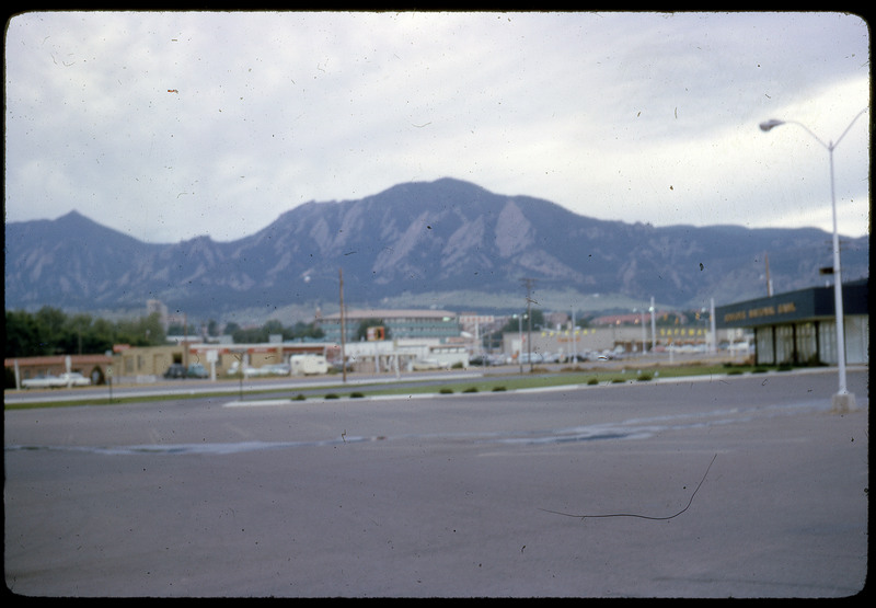 A photographic slide of a blurry view of a parking lot in front of a series of mountains.