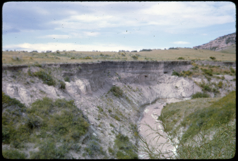 A photographic slide of a scenic view of a river cutting into a cliff.